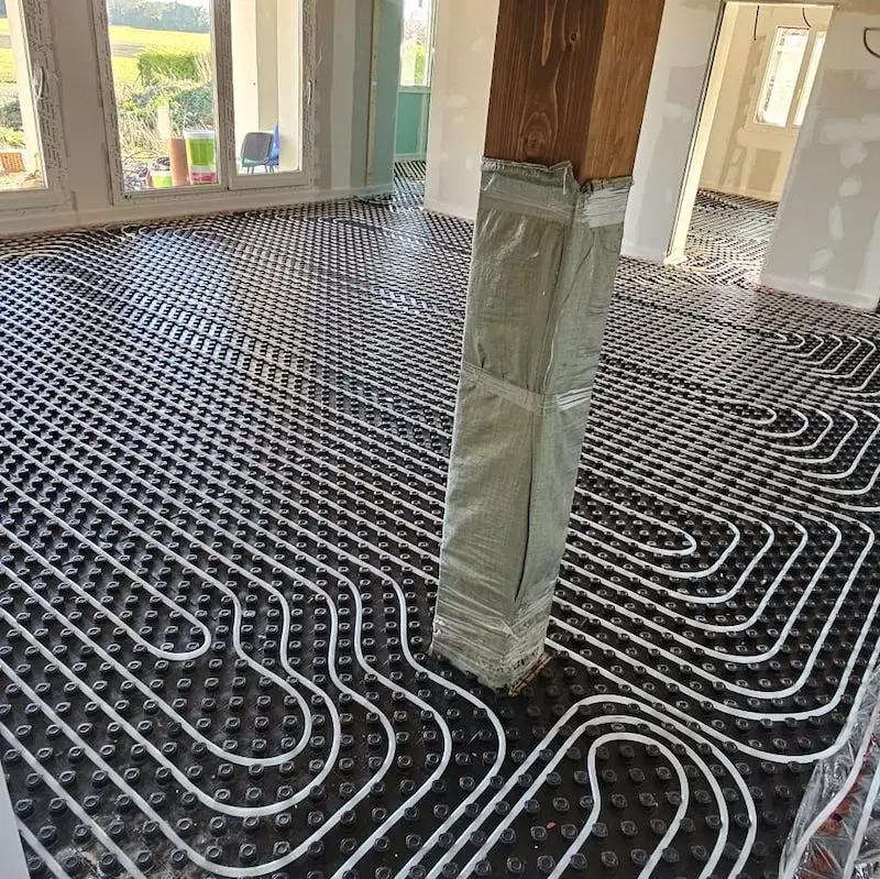 Circuitos de suelo radiante recién colocados sobre el panel aislante en una vivienda en obra
